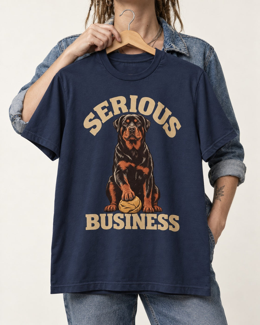 Rottweiler Serious Business Ball Under Paw Graphic T-Shirt in Navy, held up on a hanger