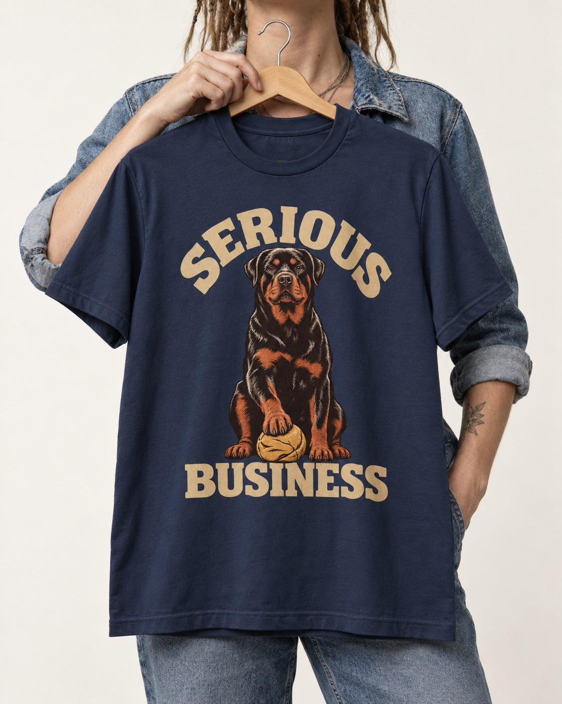 Rottweiler Serious Business Ball Under Paw Graphic T-Shirt in Navy, held up on a hanger