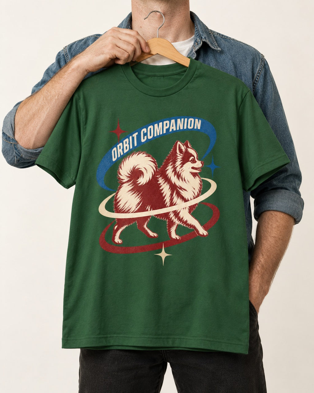 Pomeranian Orbit Companion Retro Space Graphic T-Shirt in Forest Green, held up on a hanger
