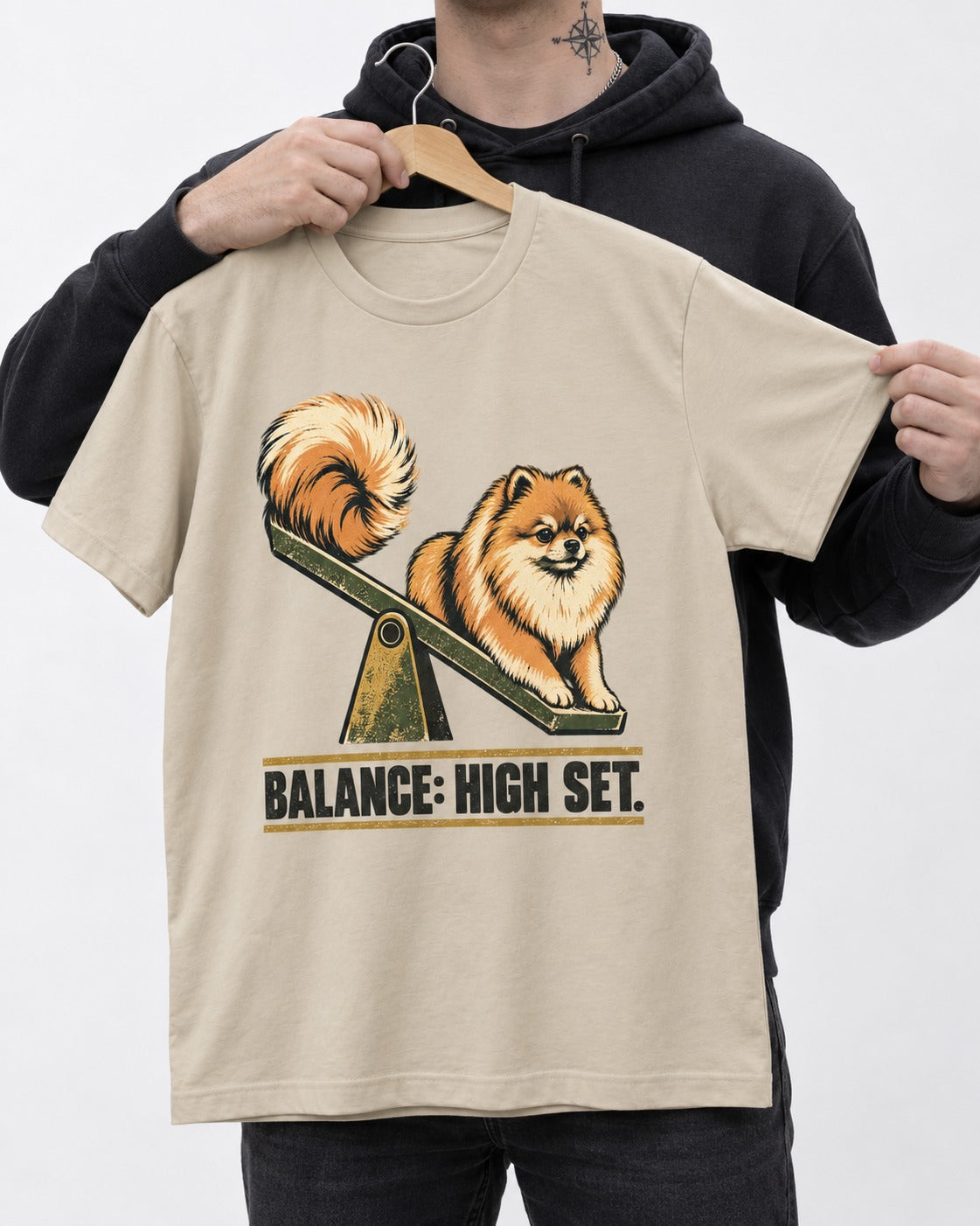 Pomeranian Balance High Set T-Shirt in Sand, held up on a hanger