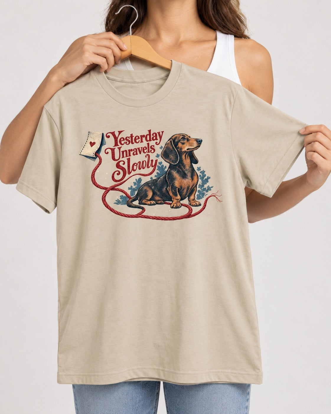Yesterday Unravels Slowly with Dachshund T-Shirt in Sand, held up on a hanger