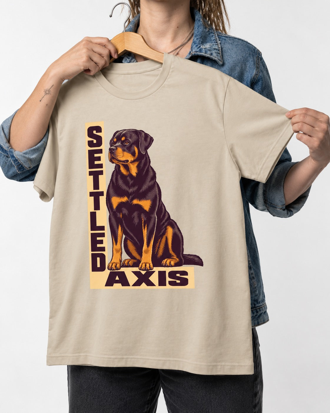 Settled Axis Rottweiler T-Shirt in Sand, held up on a hanger