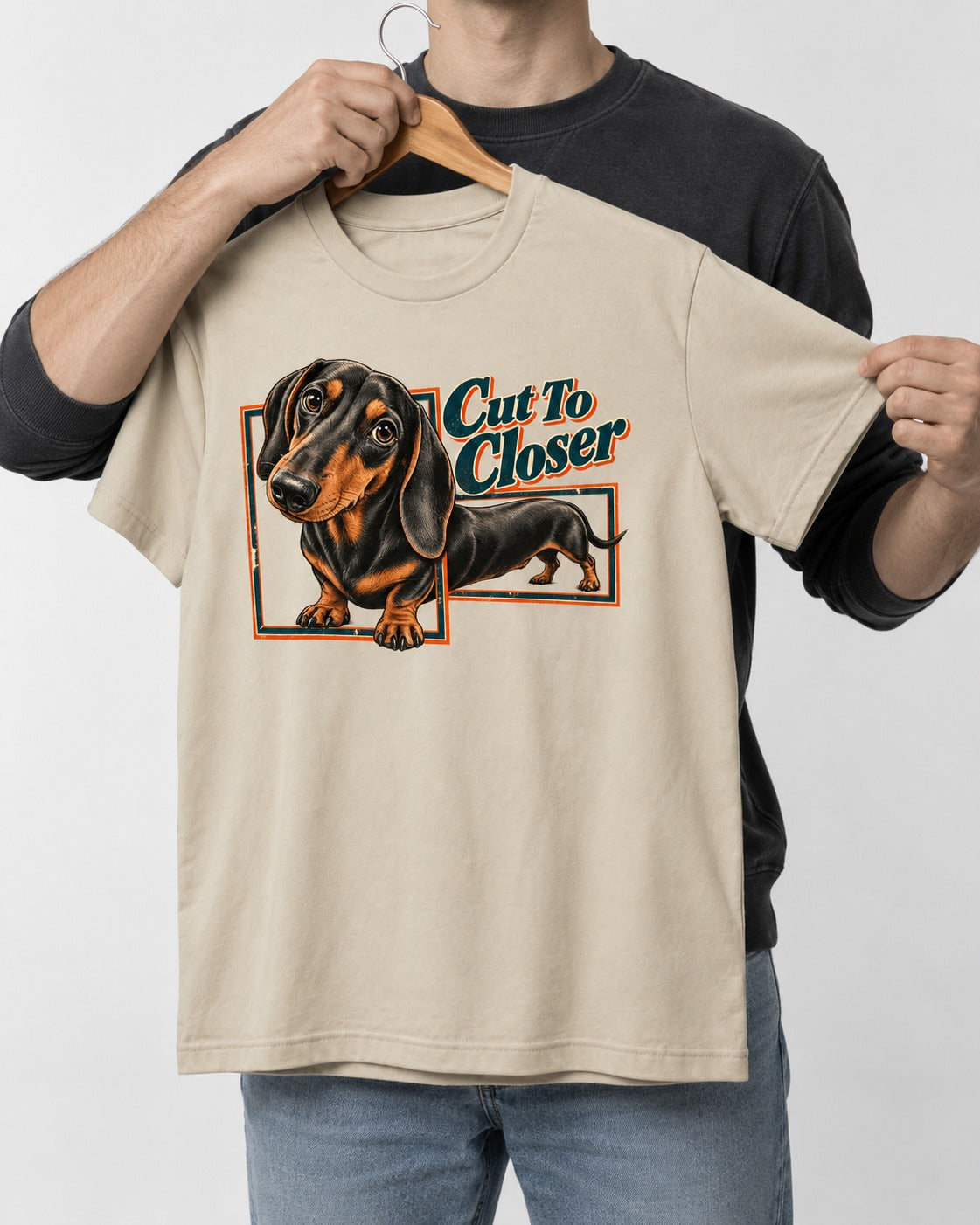 Dachshund Cut to Closer T-Shirt in Sand, held up on a hanger