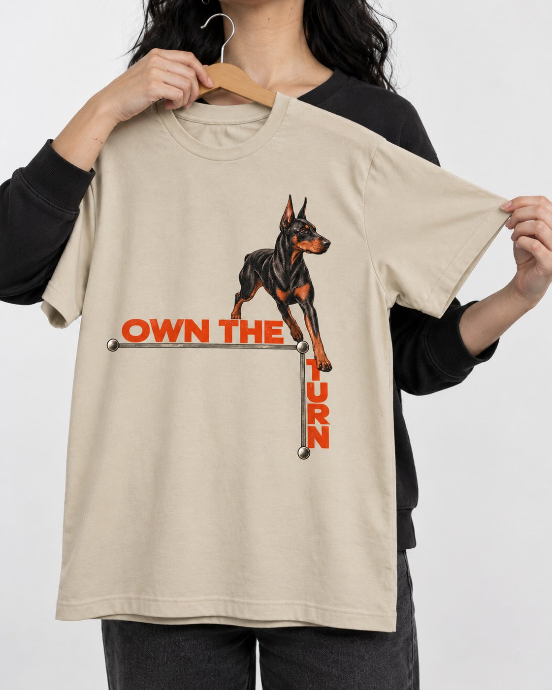 Own the Turn Doberman T-Shirt in Sand, held up on a hanger