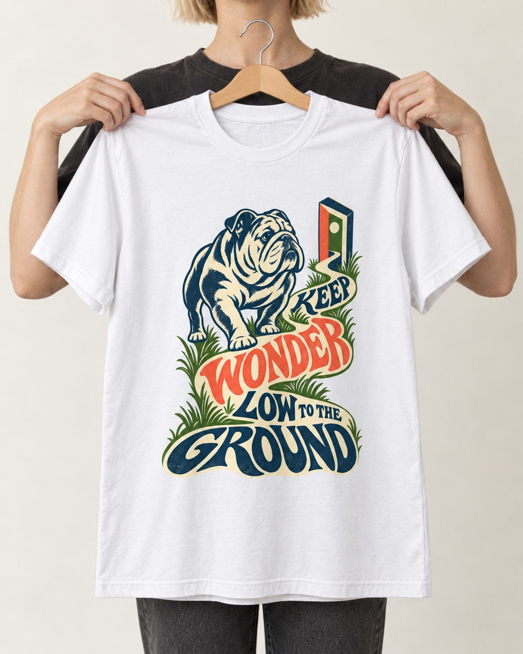 Keep Wonder Low to the Ground English Bulldog Graphic T-Shirt in White, held up on a hanger
