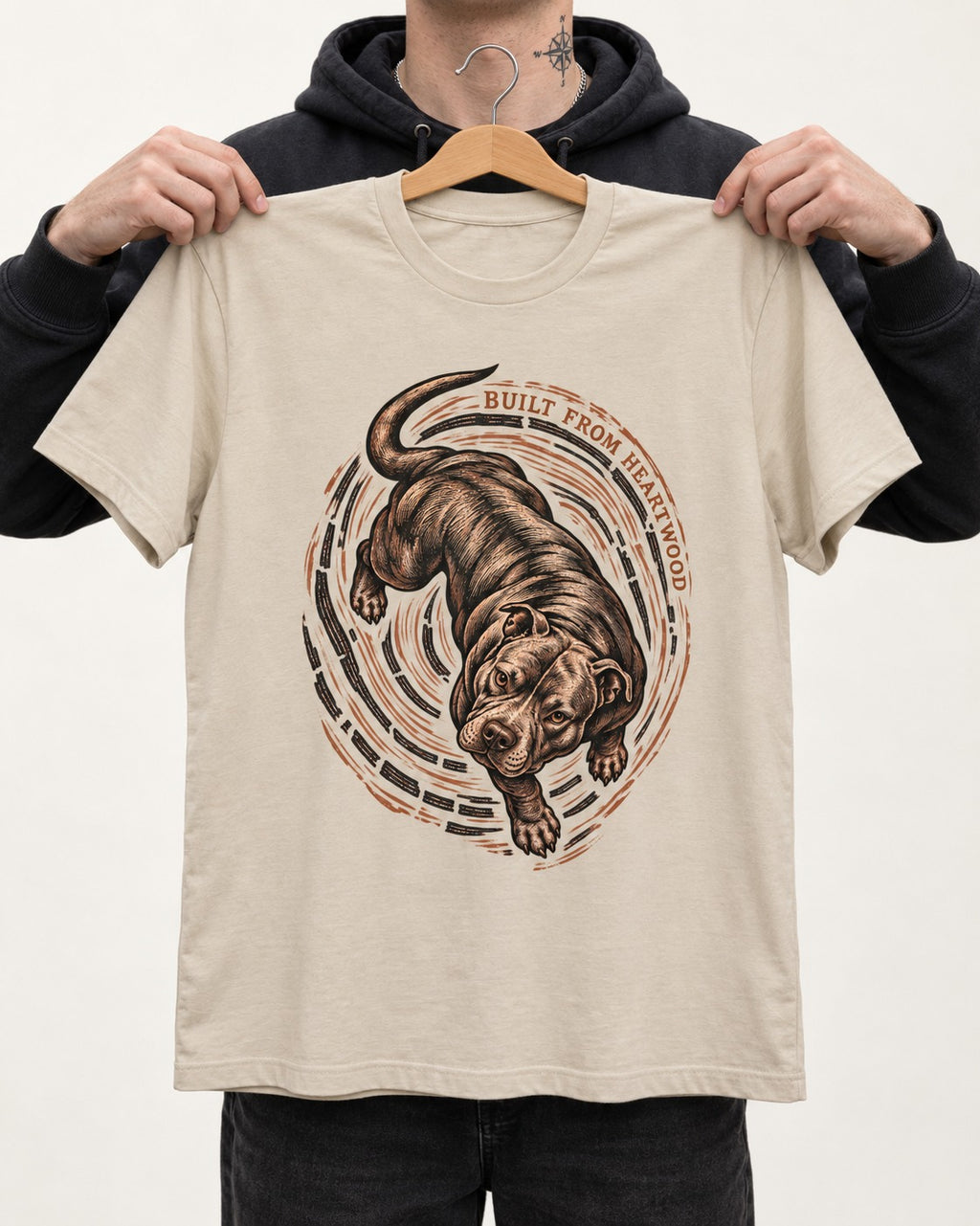 Pitbull Built From Heartwood T-Shirt in Sand, held up on a hanger