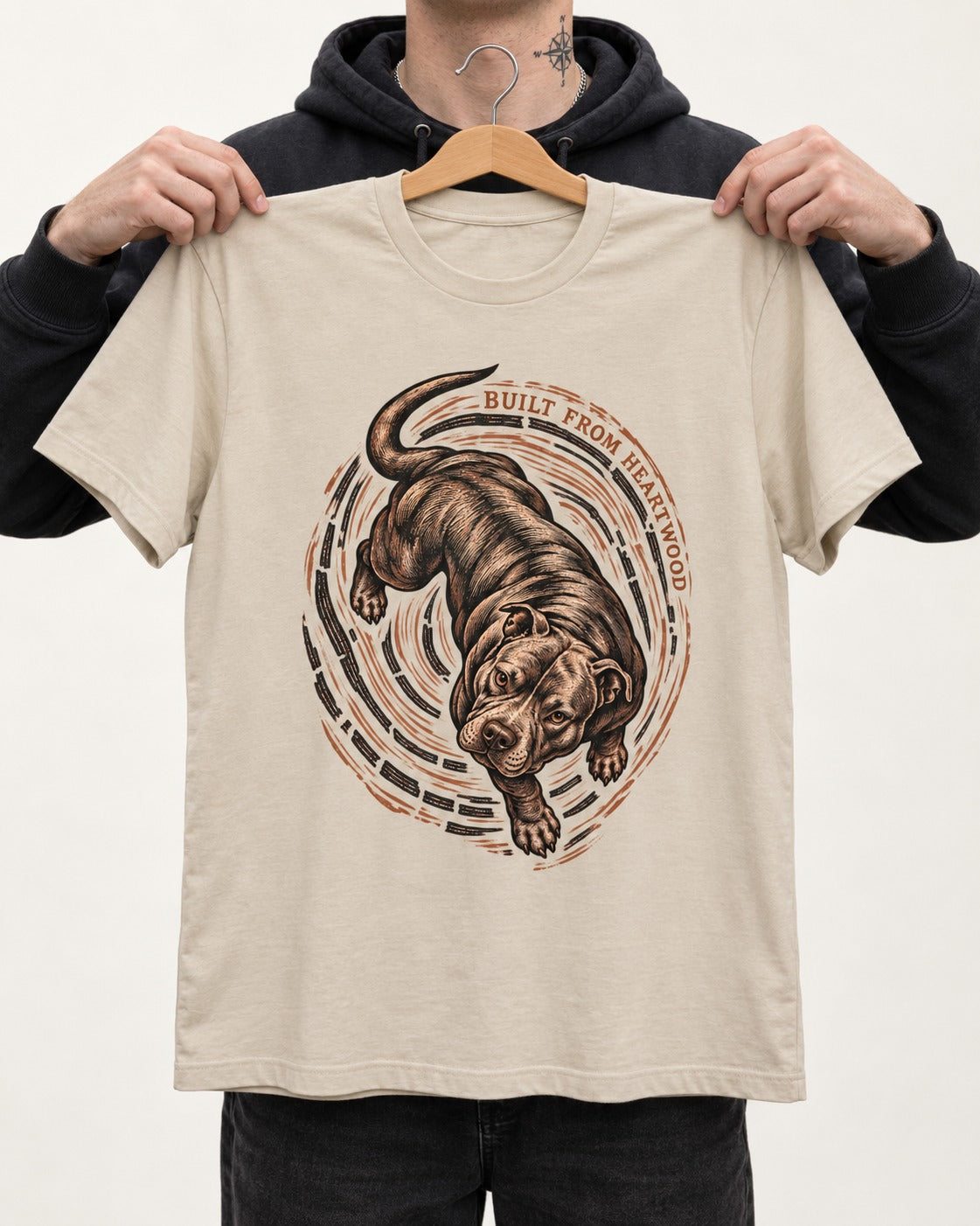 Pitbull Built From Heartwood T-Shirt in Sand, held up on a hanger