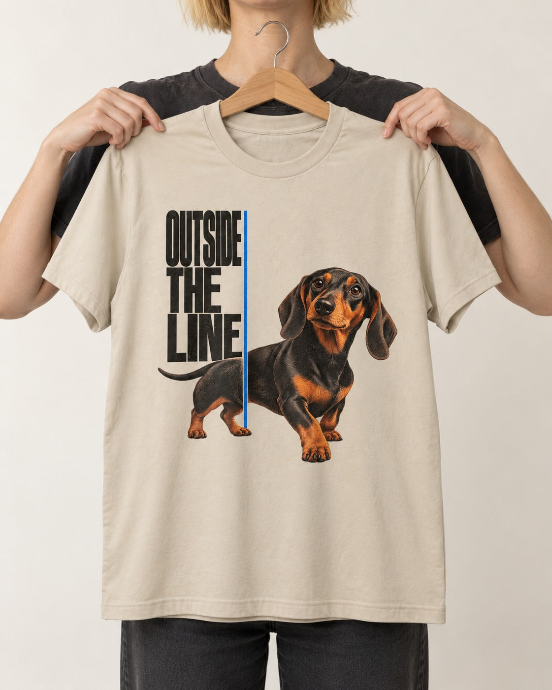 Dachshund Outside the Line T-Shirt in Sand, held up on a hanger