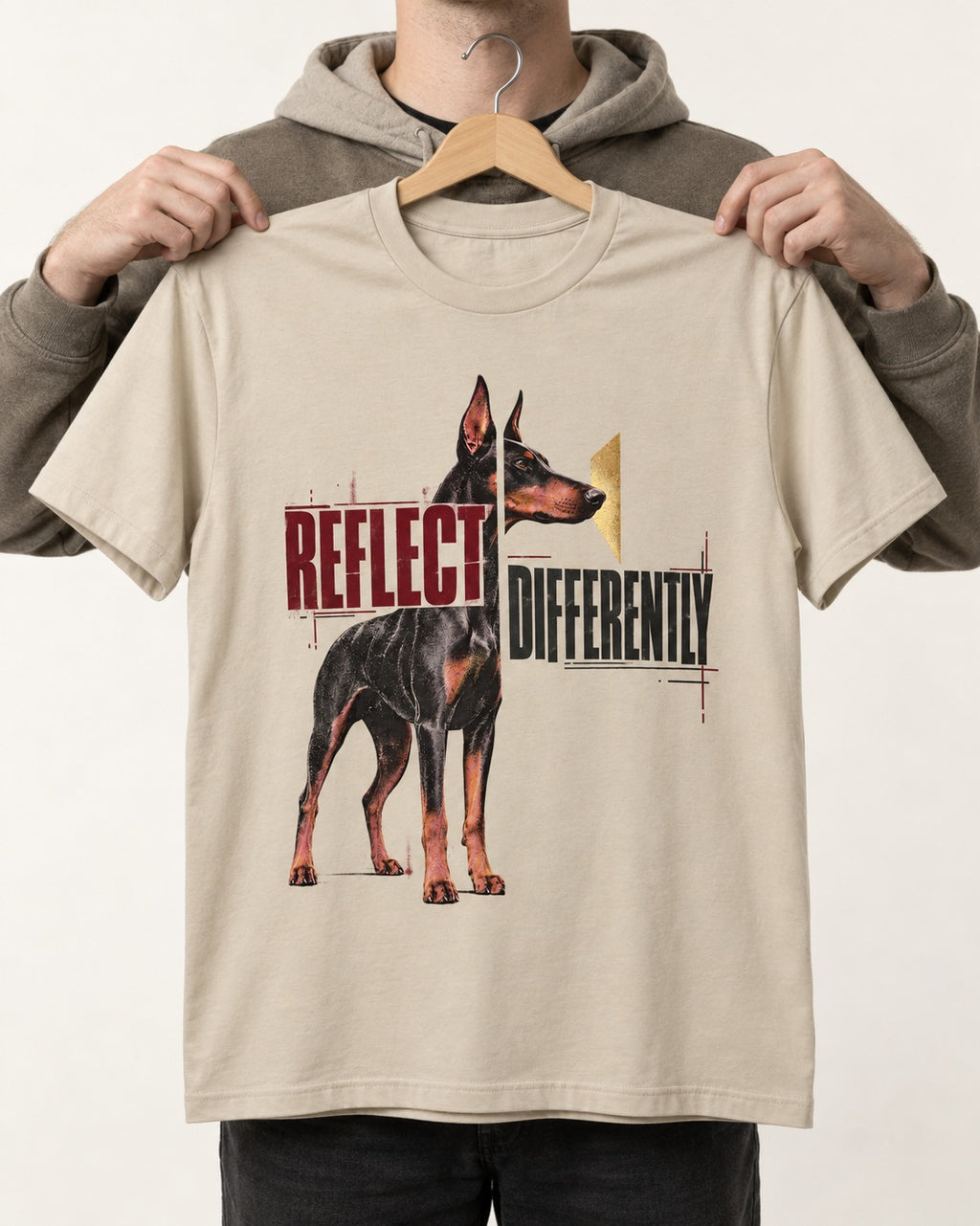 Doberman Reflects Differently T-Shirt in Sand, held up on a hanger