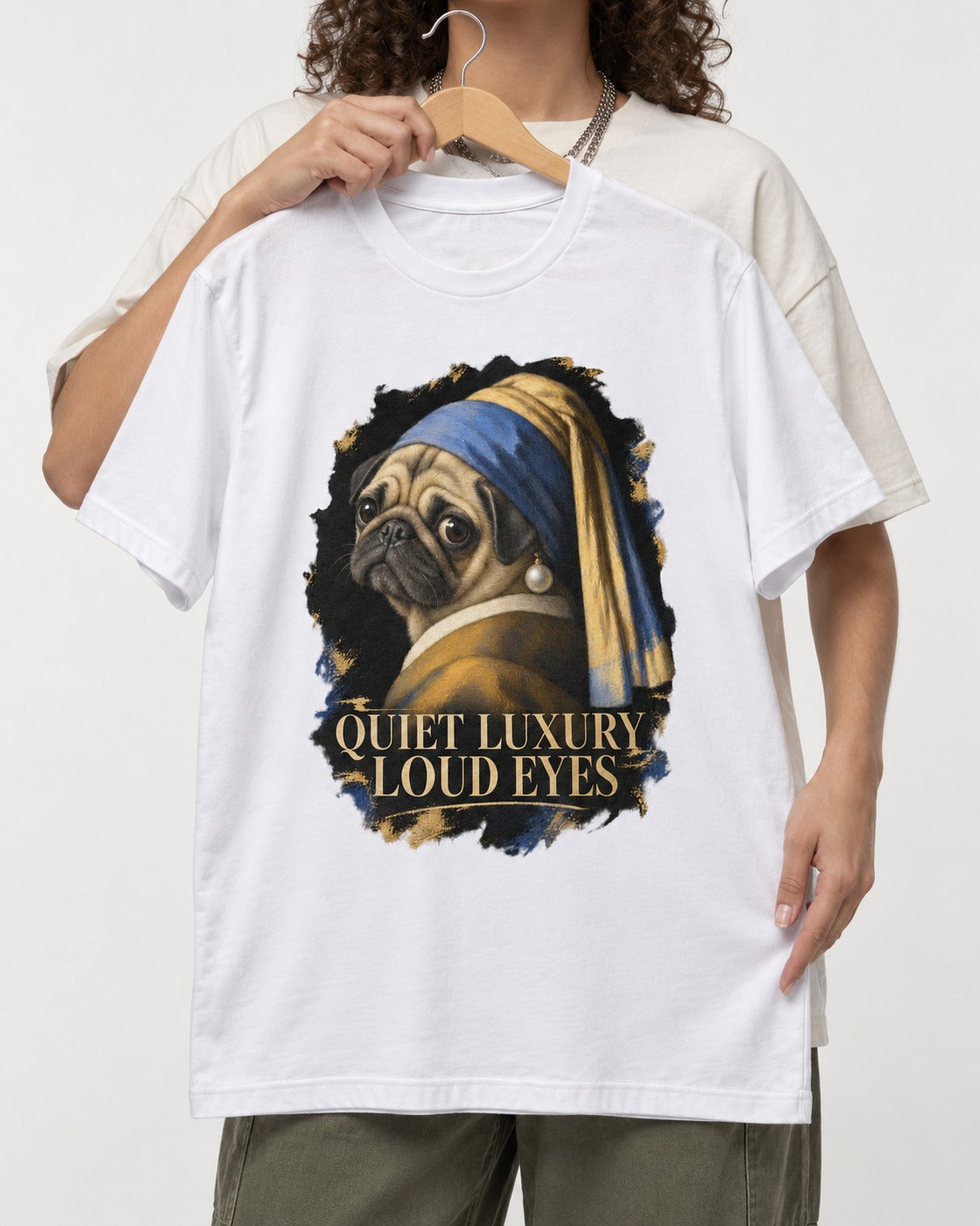 Pug Quiet Luxury Loud Eyes Pearl Portrait Graphic T-Shirt in White, held up on a hanger