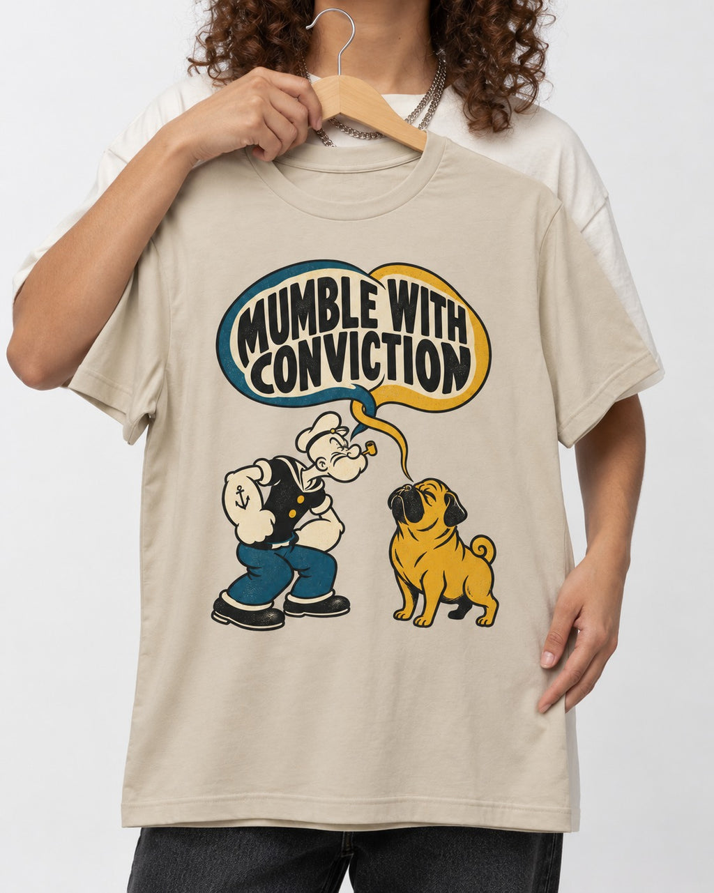 Pug Mumble with Conviction T-Shirt in Sand, held up on a hanger