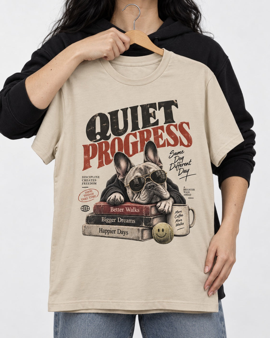 Quiet Progress Frenchie T-Shirt in Sand, held up on a hanger