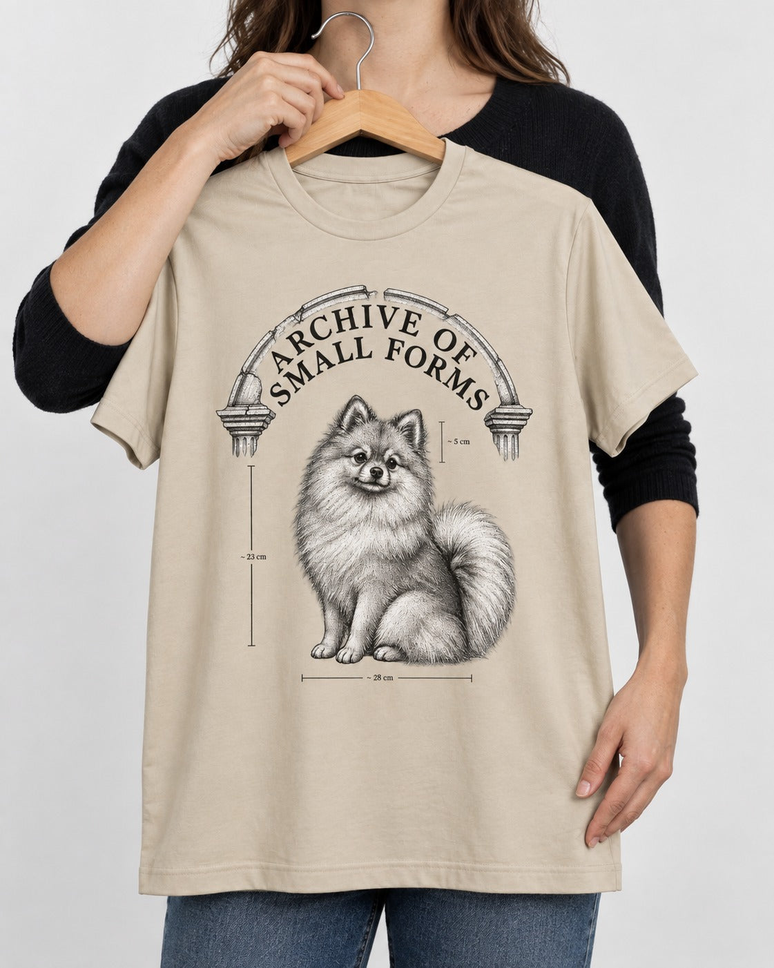 Pomeranian Archive of Small Forms T-Shirt in Sand, held up on a hanger