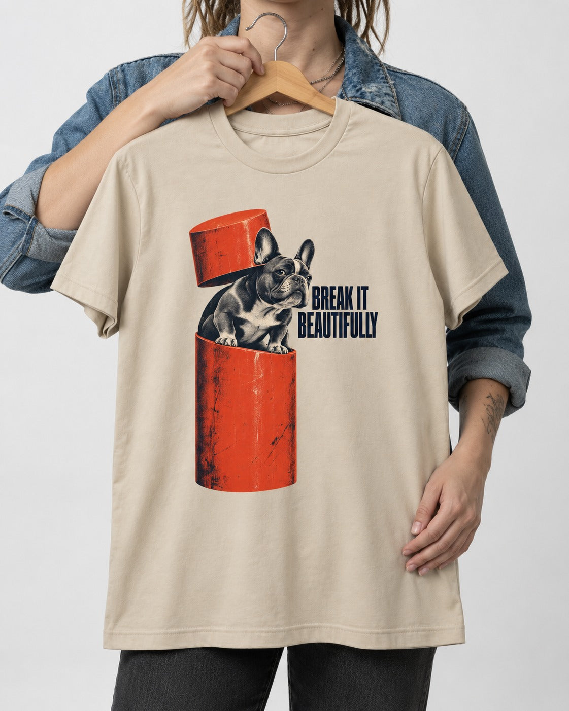 Frenchie Break It Beautifully T-Shirt in Sand, held up on a hanger
