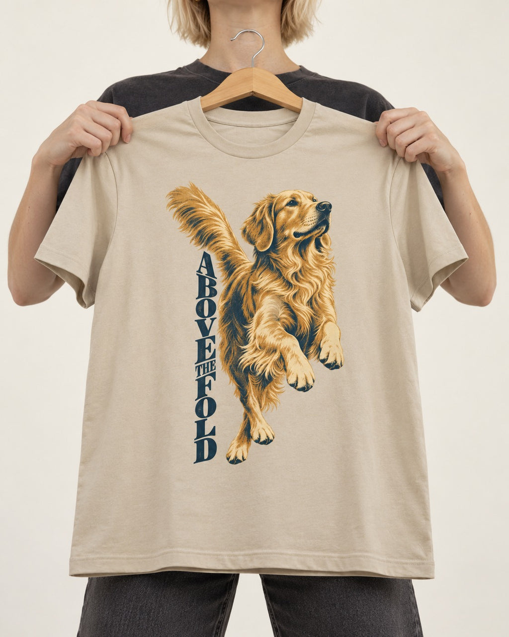 Golden Retriever Above the Fold T-Shirt in Sand, held up on a hanger