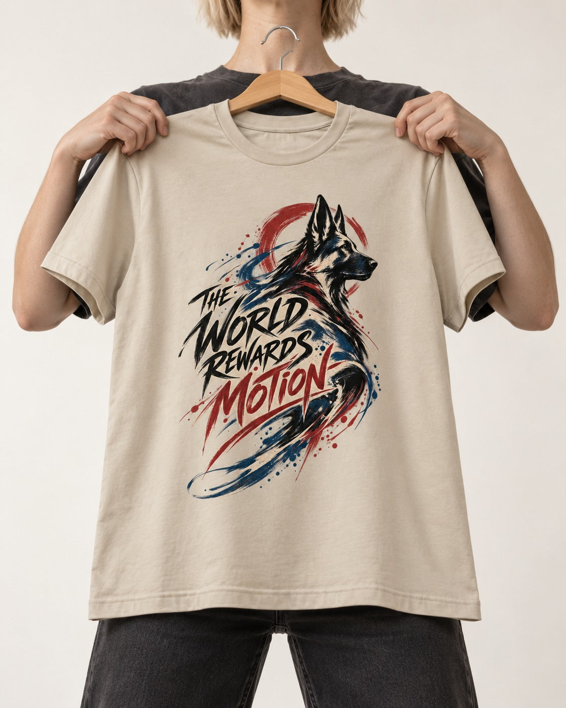 German Shepherd Dog The World Rewards Motion T-Shirt in Sand, held up on a hanger