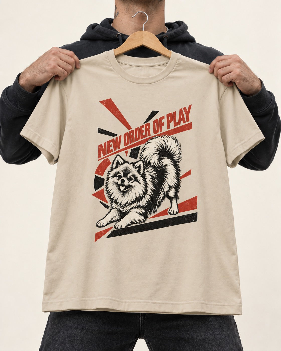 Pomeranian Order of Play T-Shirt in Sand, held up on a hanger