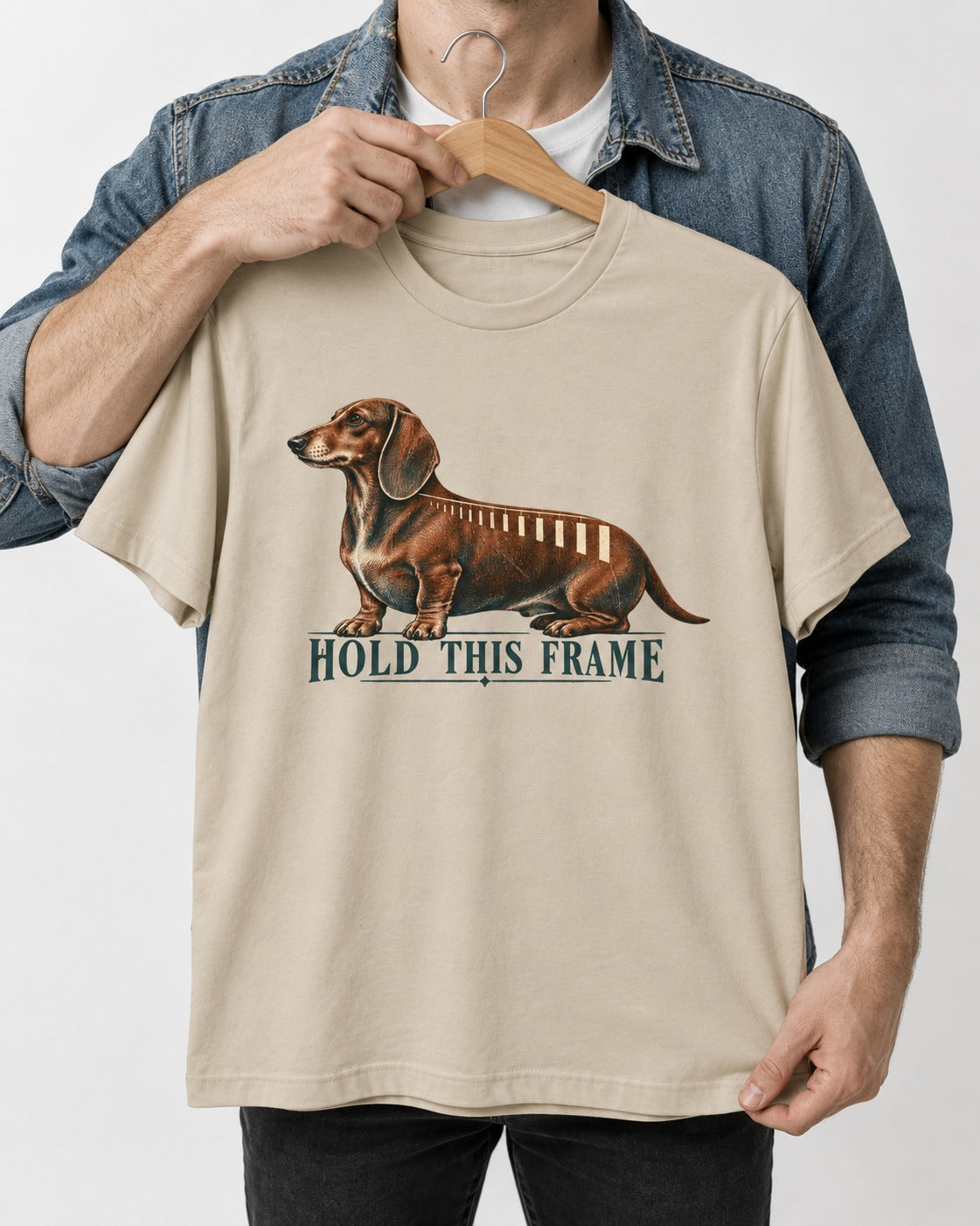 Dachshund Hold This Frame T-Shirt in Sand, held up on a hanger