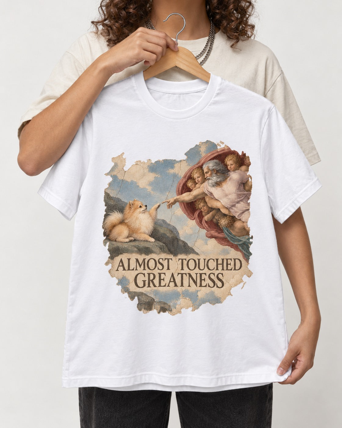 Pomeranian Almost Touched Greatness Fresco Graphic T-Shirt in White, held up on a hanger
