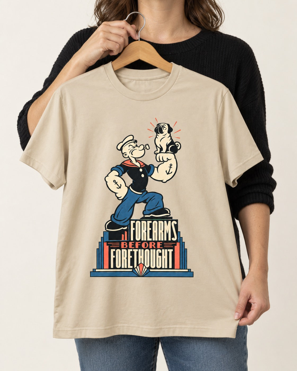 Pug Forearms Before Forethought T-Shirt in Sand, held up on a hanger