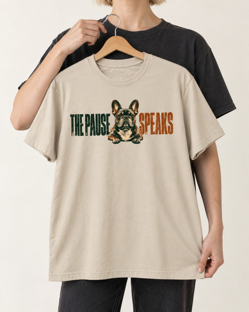 The Frenchie Pause Speaks T-Shirt in Sand, held up on a hanger