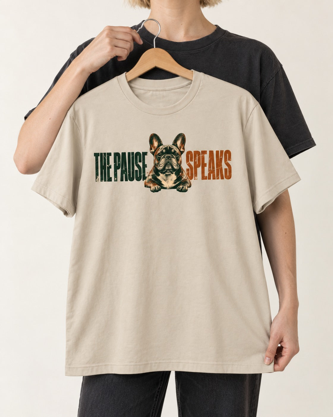 The Frenchie Pause Speaks T-Shirt in Sand, held up on a hanger