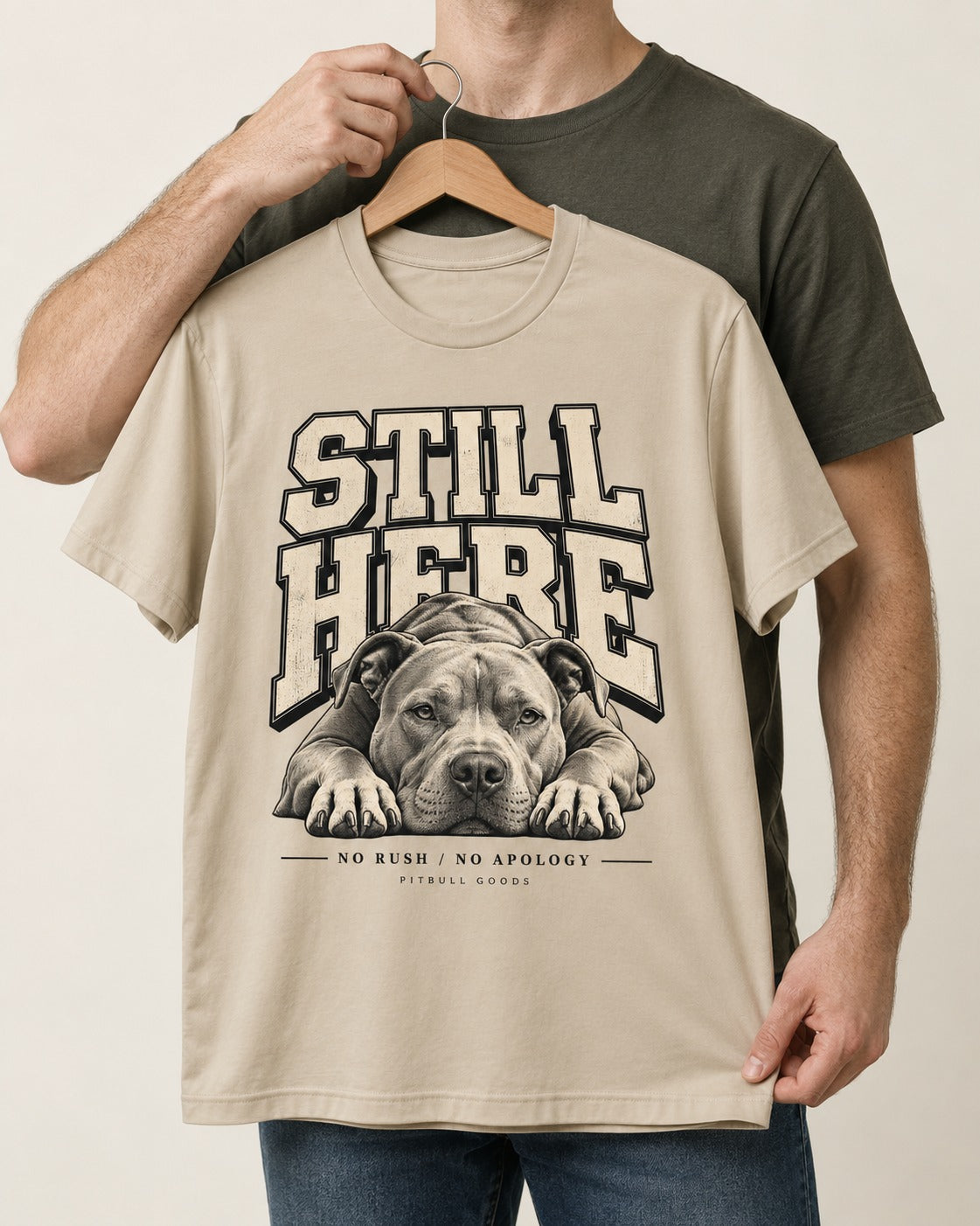 Still Here Pitbull T-Shirt in Sand, held up on a hanger
