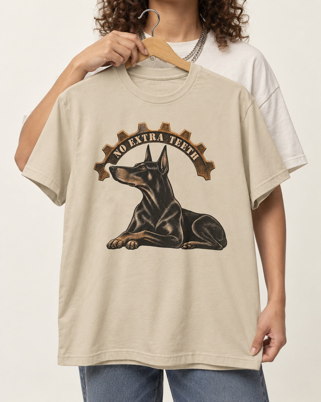 Doberman No Extra Teeth Gear Graphic T-Shirt in Sand, held up on a hanger