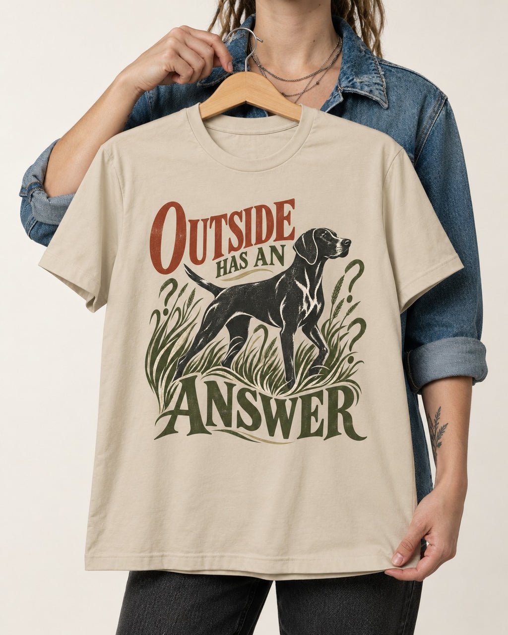Outside Has an Answer German Shorthaired Pointer T-Shirt in Sand, held up on a hanger