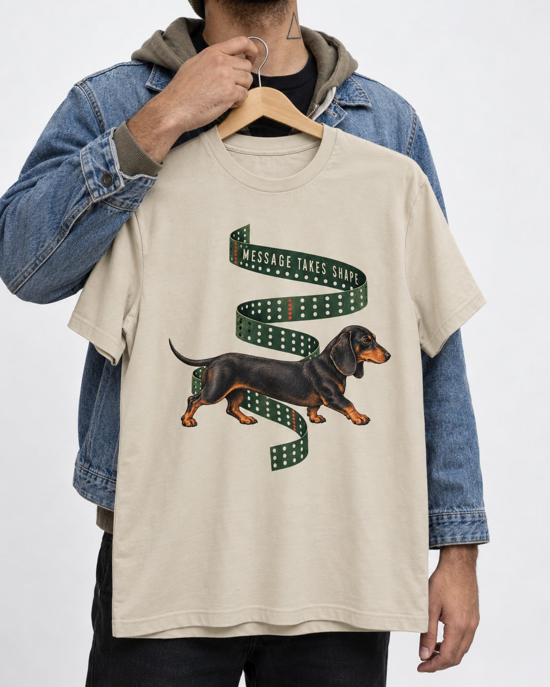 Dachshund Message Takes Shape T-Shirt in Sand, held up on a hanger