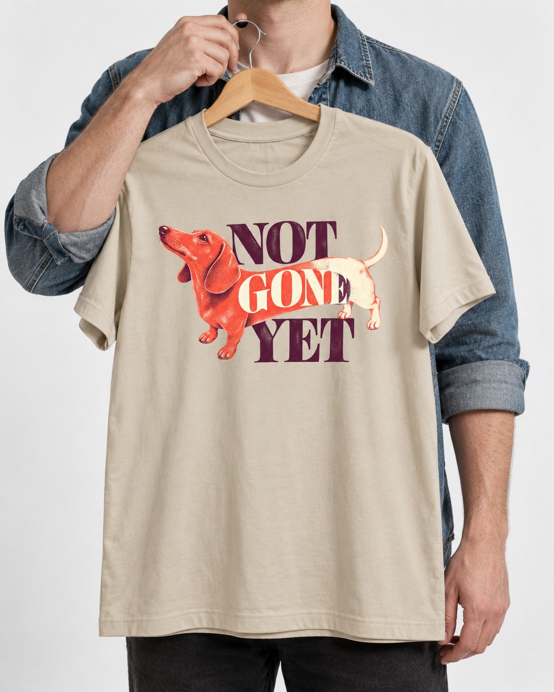 Dachshund Not Gone Yet T-Shirt in Sand, held up on a hanger