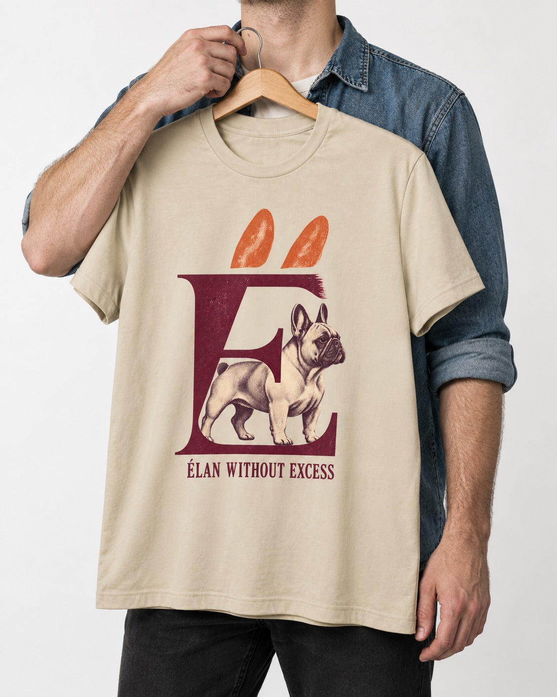 Frenchie Without Excess T-Shirt in Sand, held up on a hanger