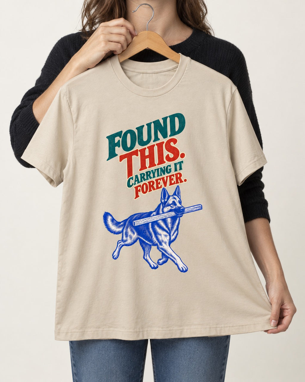 German Shepherd Dog Carrying It Forever T-Shirt in Sand, held up on a hanger