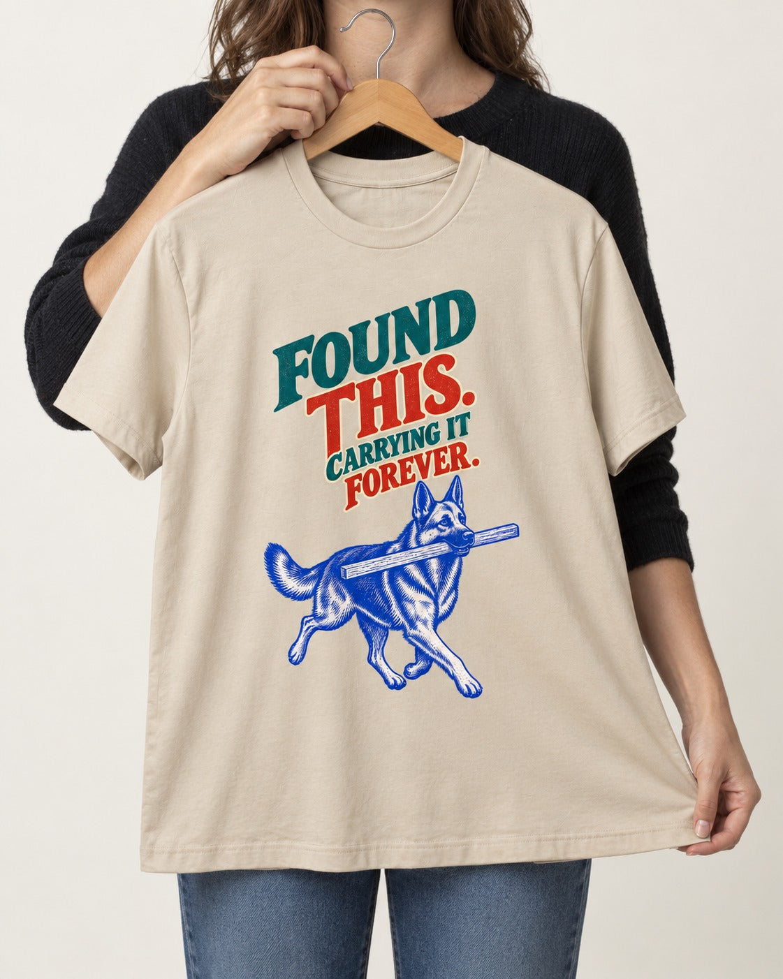 German Shepherd Dog Carrying It Forever T-Shirt in Sand, held up on a hanger
