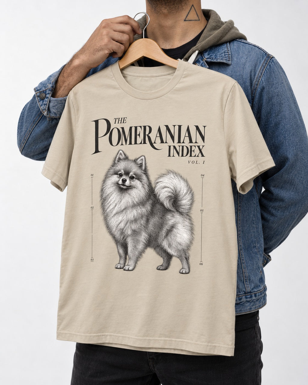 The Pomeranian Index T-Shirt in Sand, held up on a hanger
