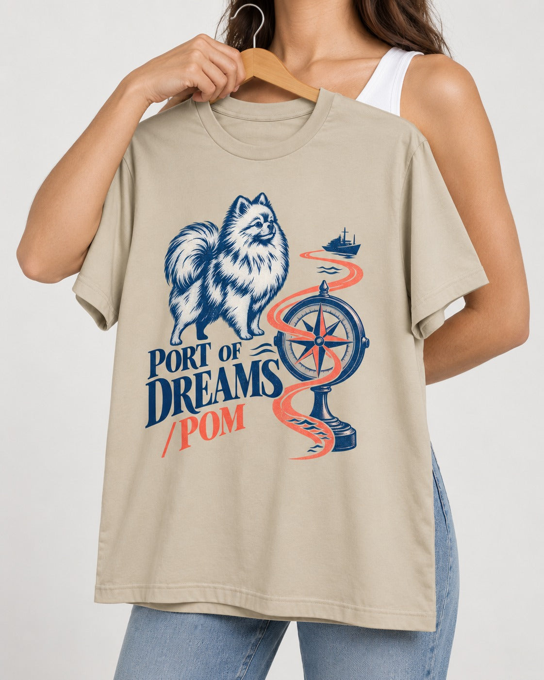Pomeranian Port of Dreams T-Shirt in Sand, held up on a hanger