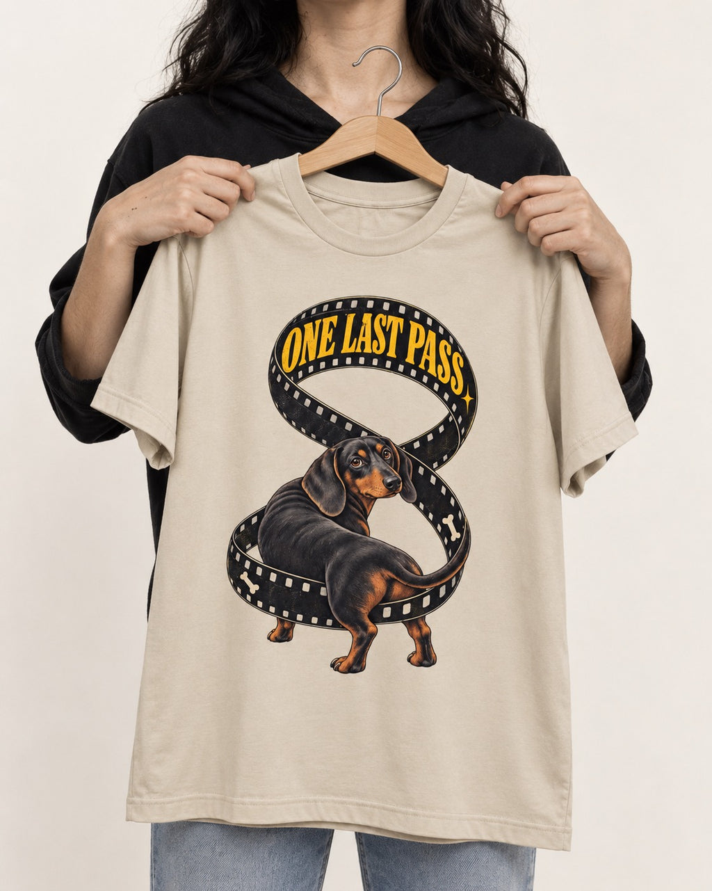 Dachshund's One Last Pass T-Shirt in Sand, held up on a hanger
