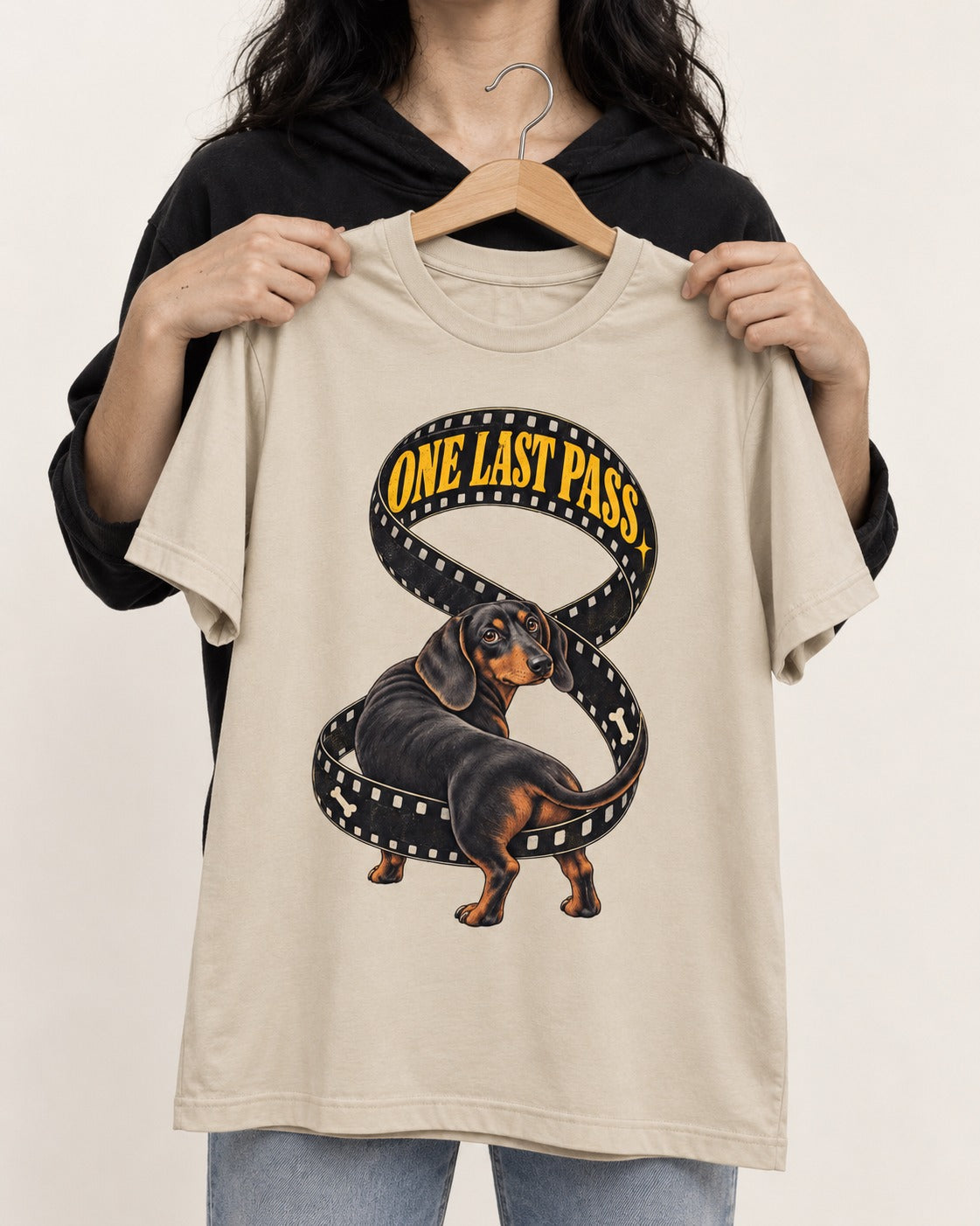 Dachshund's One Last Pass T-Shirt in Sand, held up on a hanger