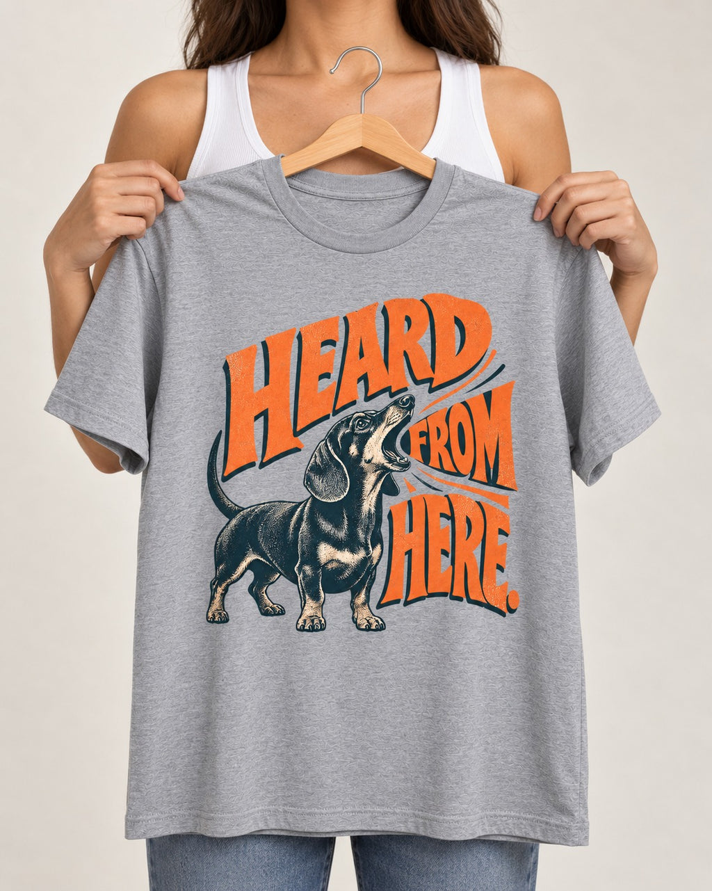 Dachshund Heard From Here T-Shirt in Sport Grey, held up on a hanger