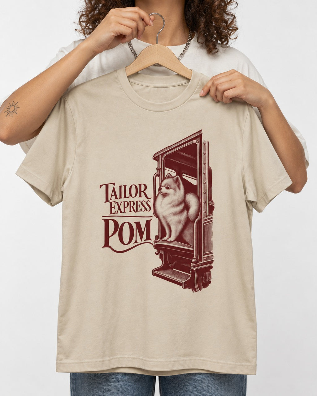 Pomeranian Express T-Shirt in Sand, held up on a hanger