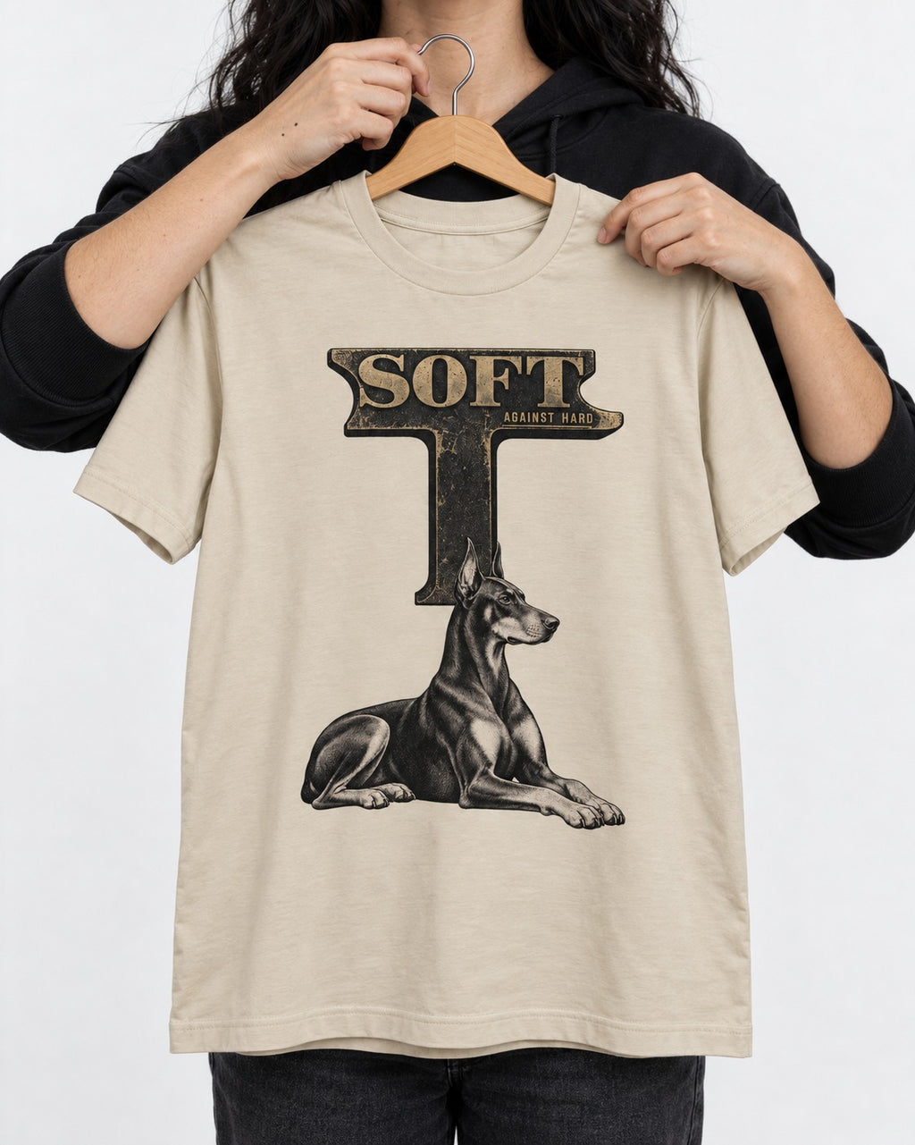 Soft Against Hard Doberman T-Shirt in Sand, held up on a hanger