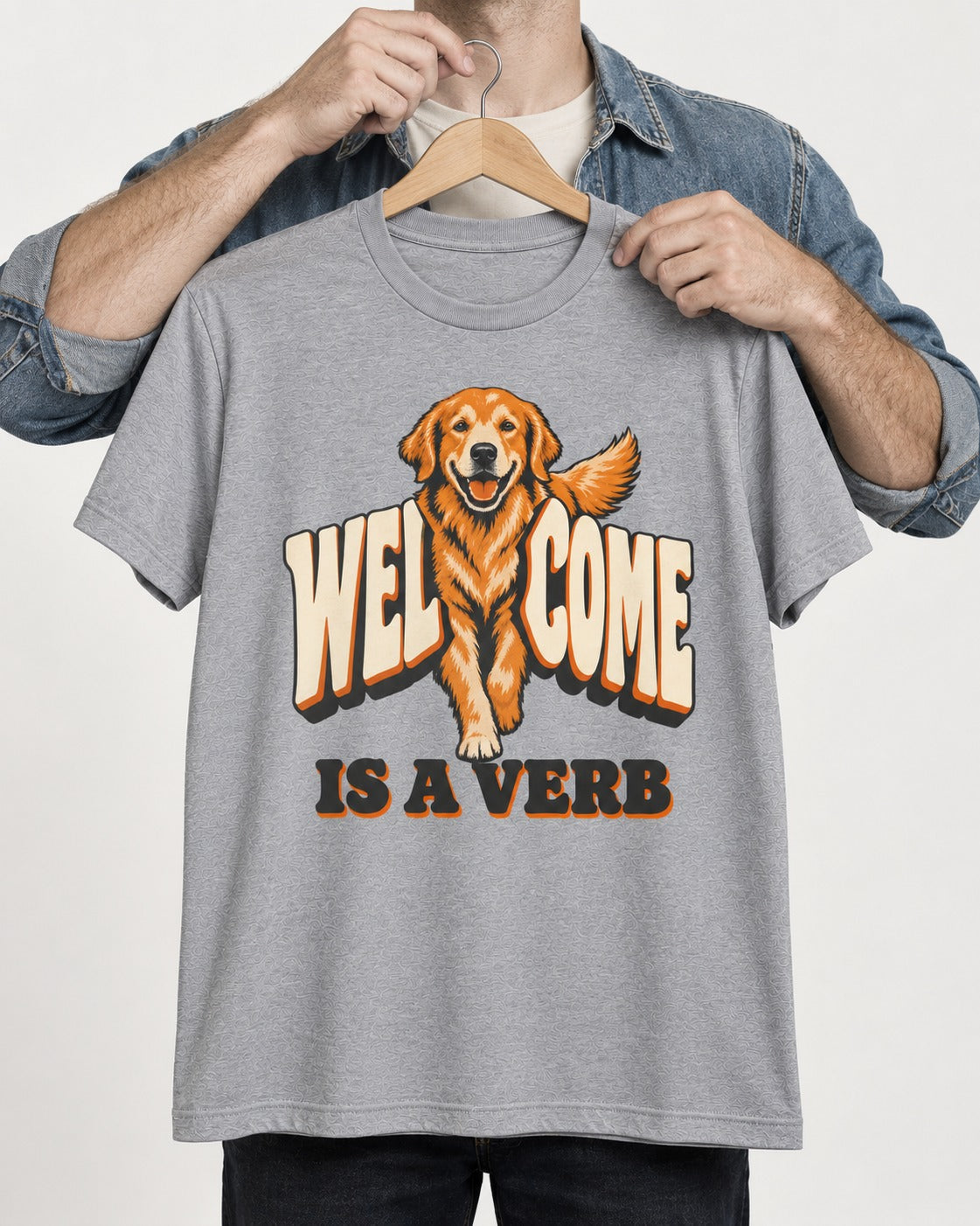 Golden Retriever Welcome Is a Verb T-Shirt in Sport Grey, held up on a hanger