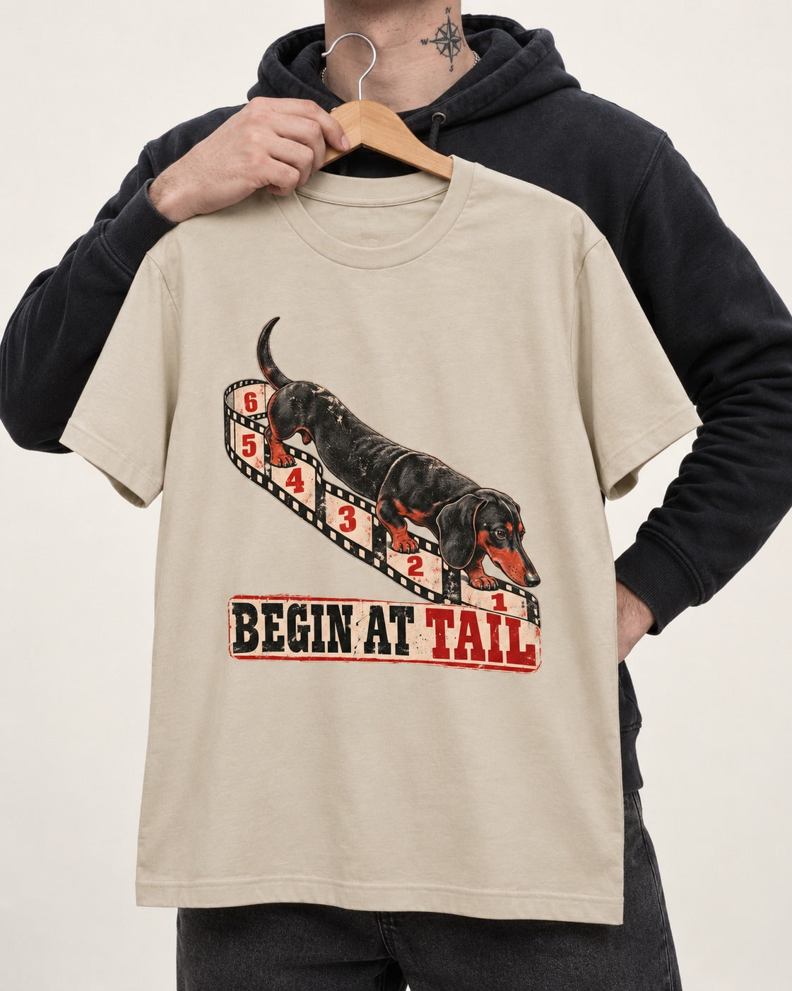 Begin at Tail Dachshund T-Shirt in Sand, held up on a hanger