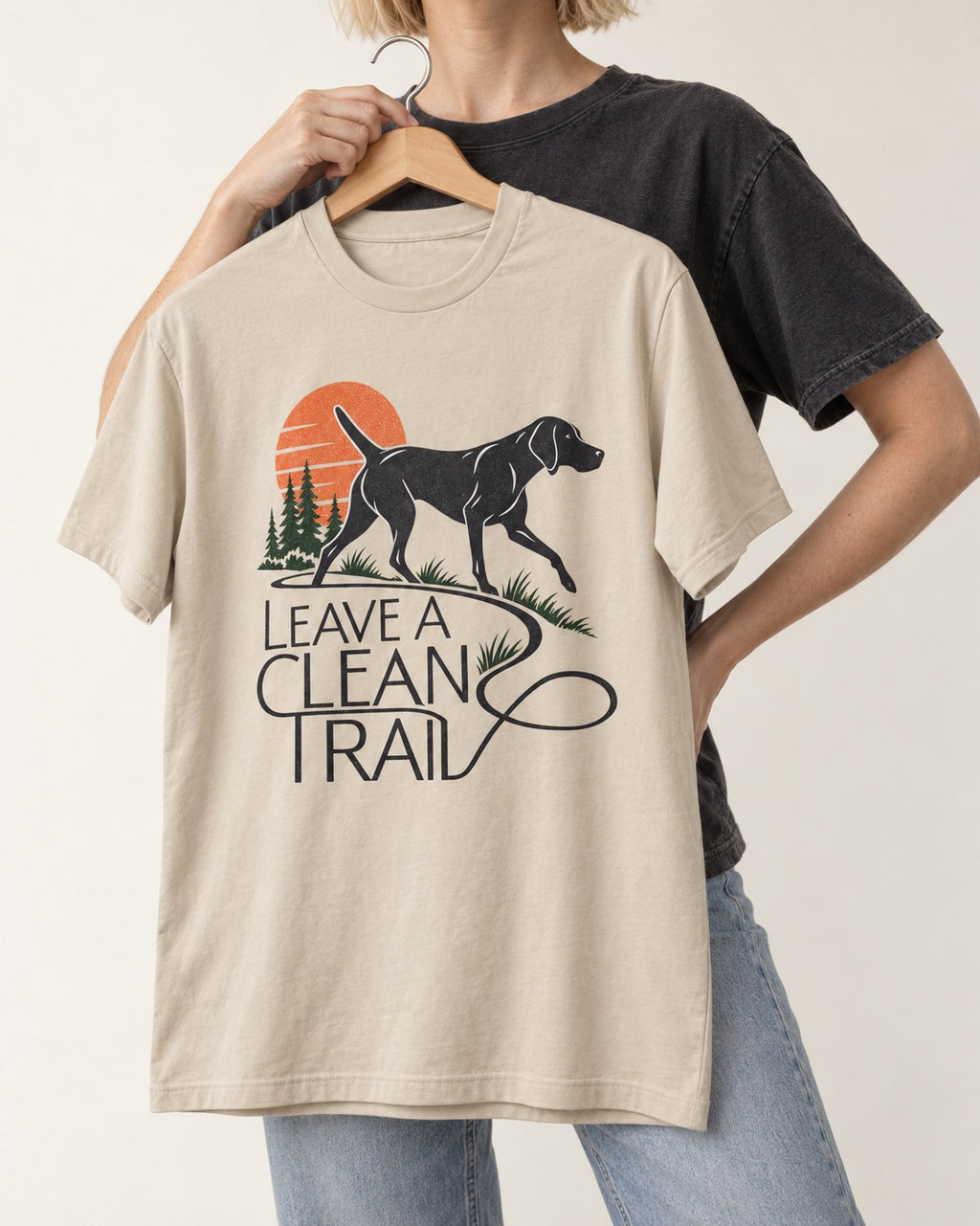 Leave a Clean Trail German Shorthaired Pointer T-Shirt in Sand, held up on a hanger