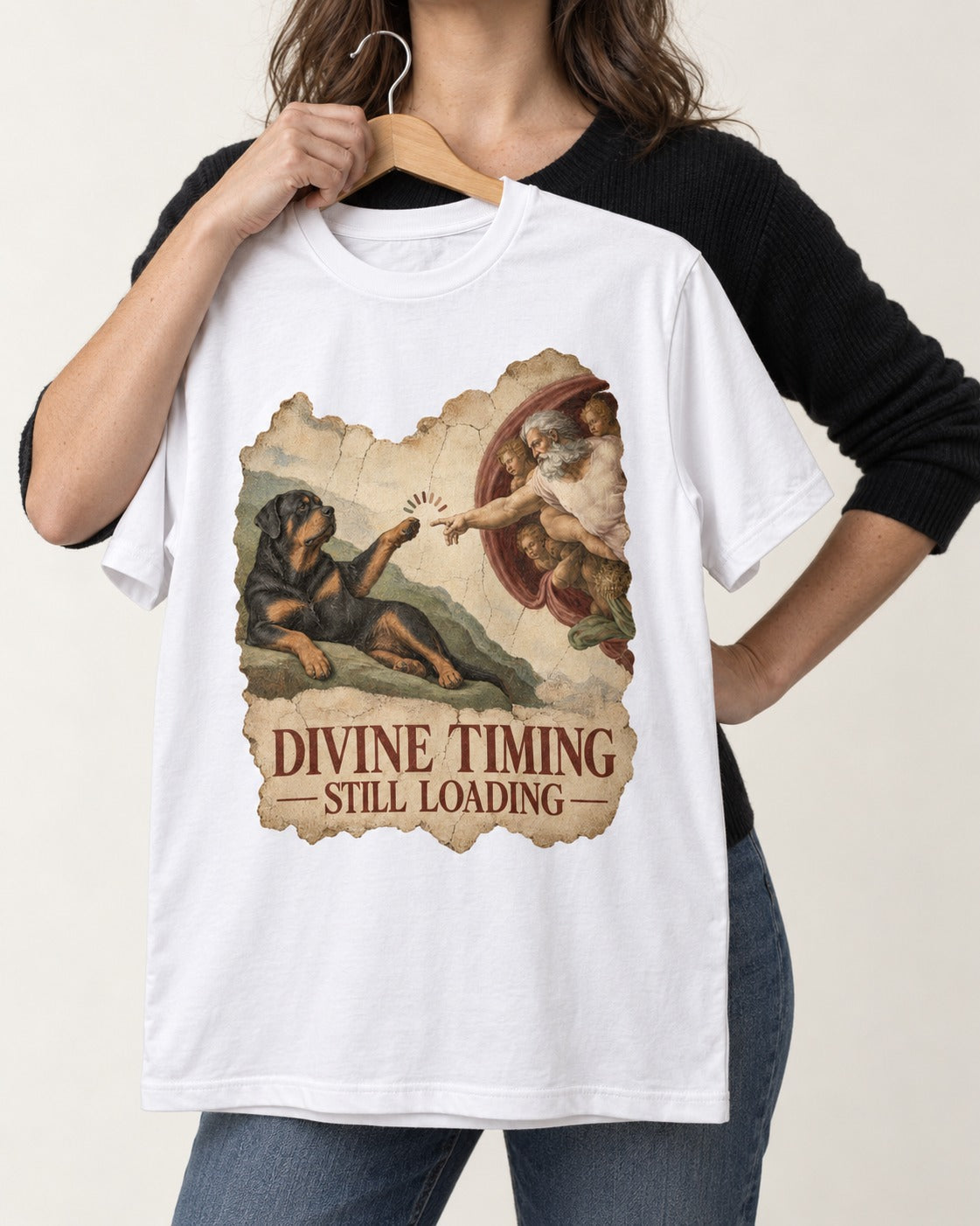 Rottweiler Divine Timing Still Loading Creation Parody Graphic T-Shirt in White, held up on a hanger