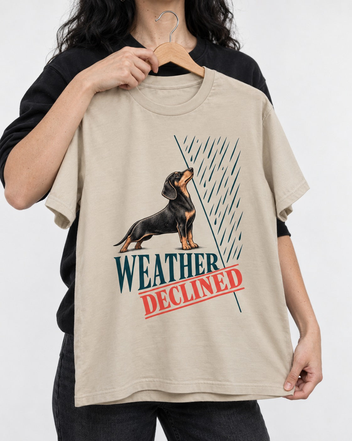Weather Declined by Dachshund T-Shirt in Sand, held up on a hanger