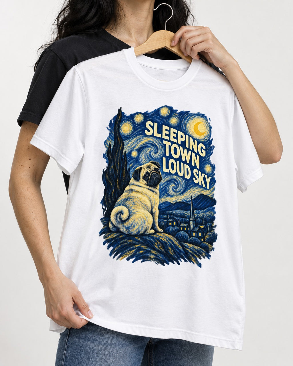 Pug Sleeping Town Loud Sky Starry Night Graphic T-Shirt in White, held up on a hanger