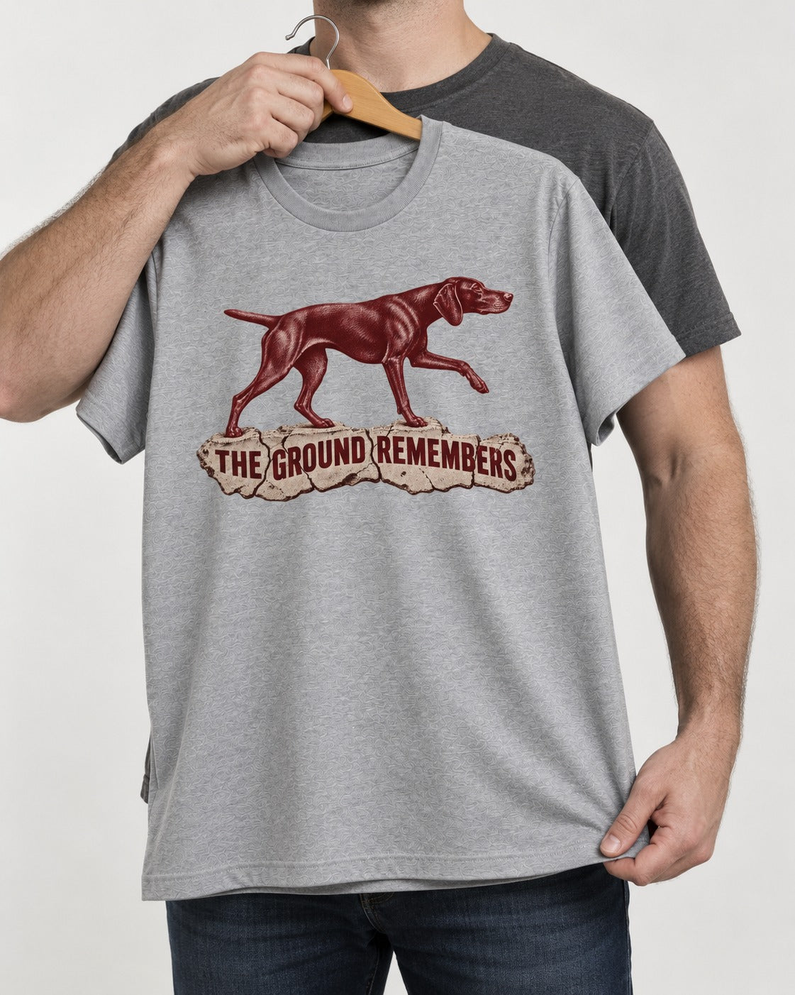 The Ground Remembers German Shorthaired Pointer T-Shirt in Sport Grey, held up on a hanger