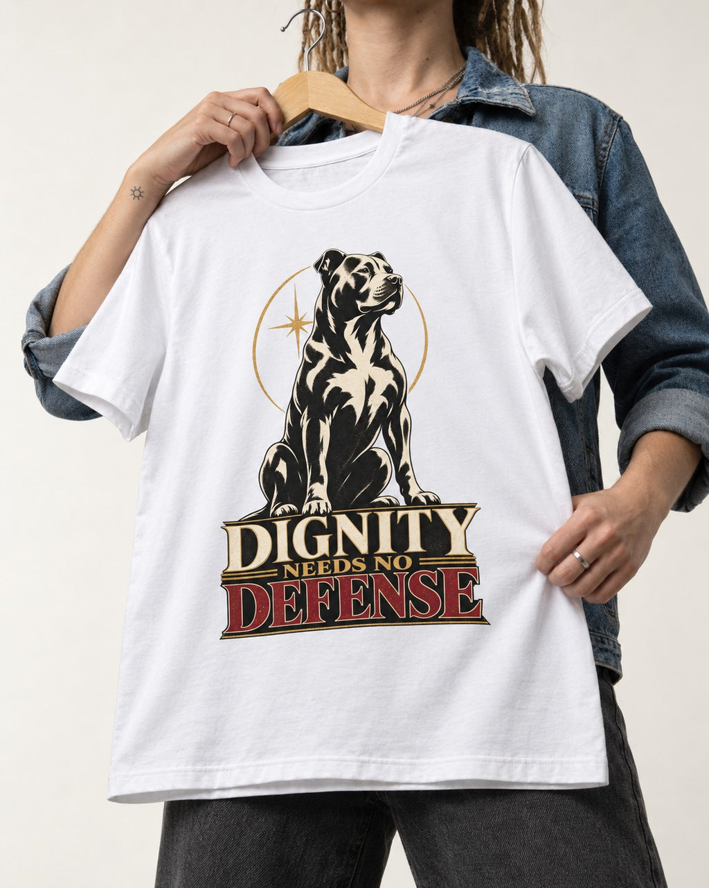 Pitbull Dignity Needs No Defense Seated Emblem Graphic T-Shirt in White, held up on a hanger