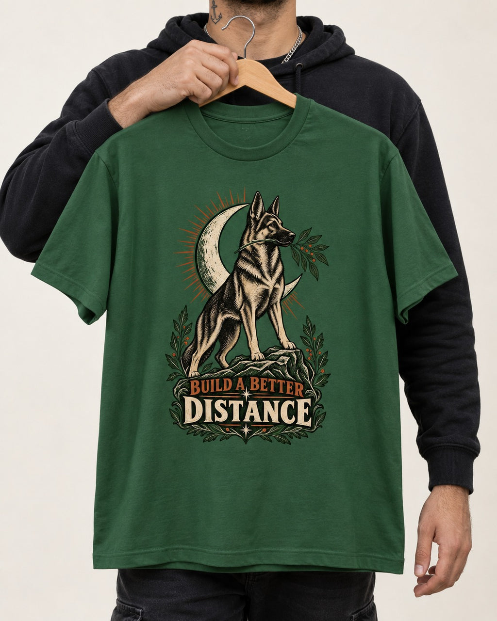Build A Better Distance Moon Woodcut German Shepherd Dog Graphic T-Shirt in Forest Green, held up on a hanger